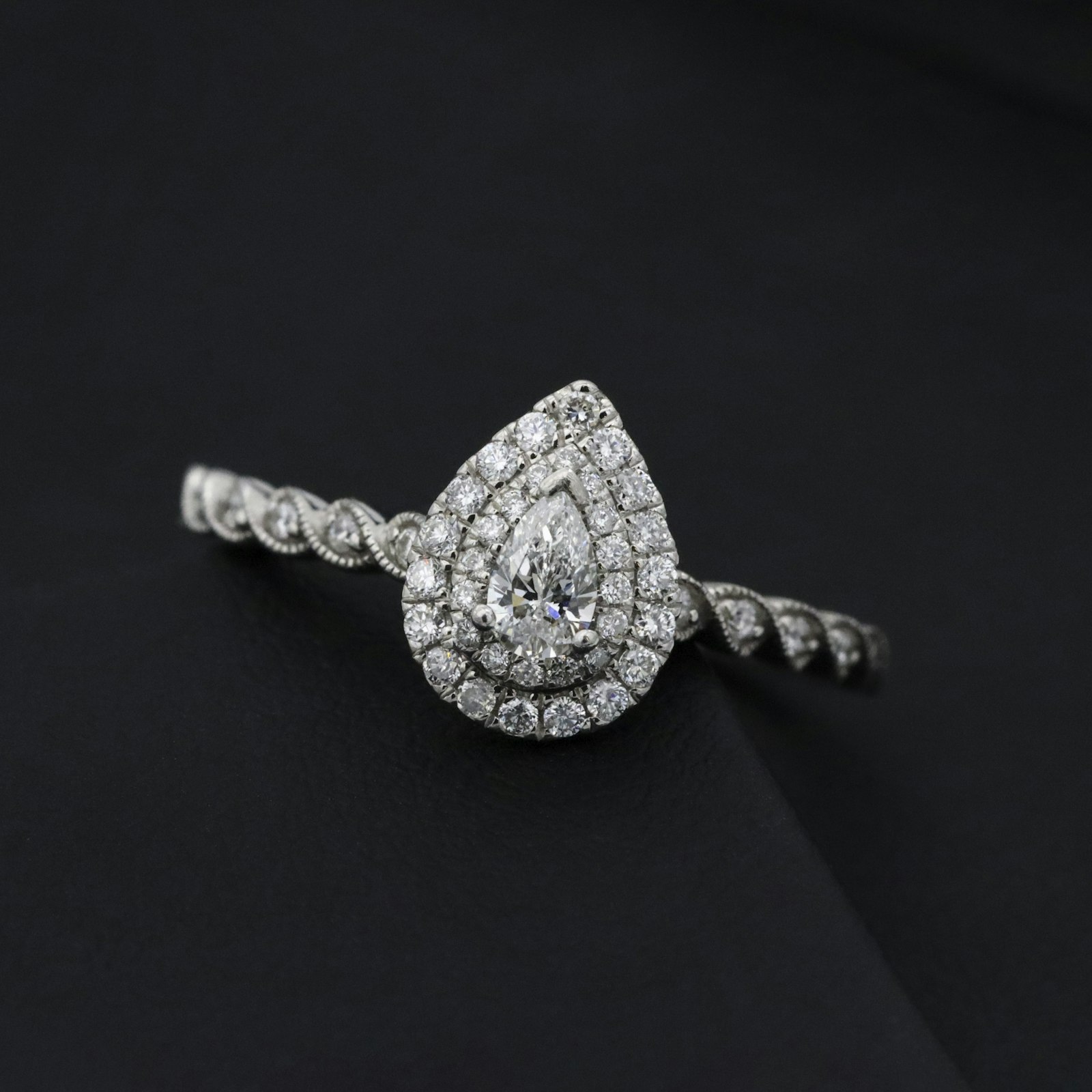 A pear-shaped diamond halo ring on black